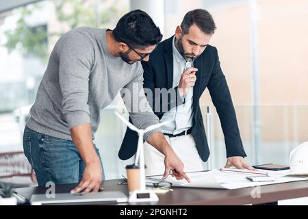 Architectes ayant une discussion sur le plan au bureau avec le modèle d'éolienne sur le bureau Banque D'Images