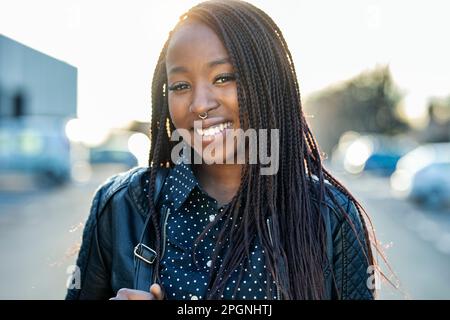 Bonne jeune femme aux cheveux tressés le jour ensoleillé Banque D'Images