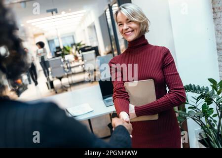 Une femme d'affaires heureuse qui se mêle à un collègue sur le lieu de travail Banque D'Images