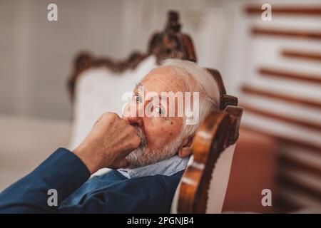 Senior man sitting on chair at home Banque D'Images