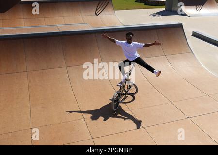 Un jeune homme qui s'équilibre sur un vélo BMX au skate Park Banque D'Images