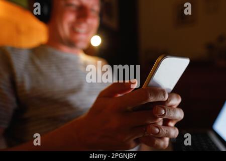 Mains d'un homme utilisant un smartphone à la maison Banque D'Images