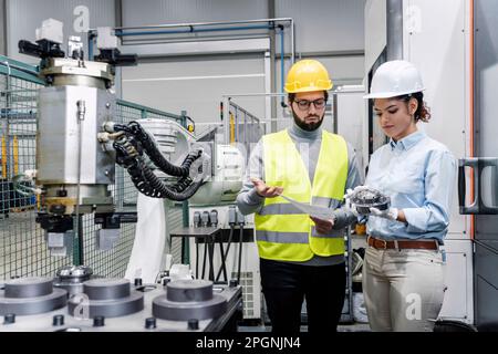 Femme d'affaires montrant une pièce de machine à l'ingénieur en usine Banque D'Images