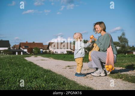 Femme souriante donnant de la pomme à son fils sur la piste de marche Banque D'Images