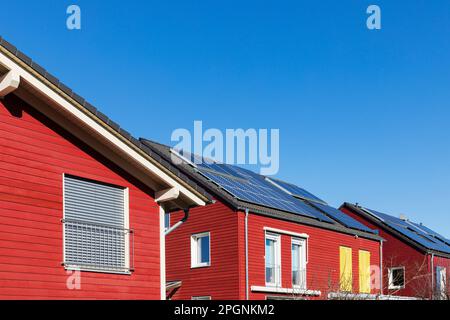 Allemagne, Rhénanie-du-Nord Westphalie, Cologne, rangée de maisons en bois peintes en rouge avec panneaux de toit solaires Banque D'Images