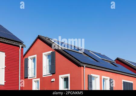 Allemagne, Rhénanie-du-Nord Westphalie, Cologne, rangée de maisons en bois peintes en rouge avec panneaux de toit solaires Banque D'Images