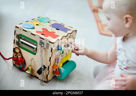 Montessori Sensory Toy for Fine Motor Skills. Bébé apprend des chiffres sur un jeu de puzzle en montrant un petit stylo sur l'horloge Banque D'Images