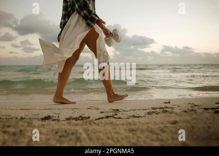 Femme marchant pieds nus sur le sable près du rivage à la plage Banque D'Images