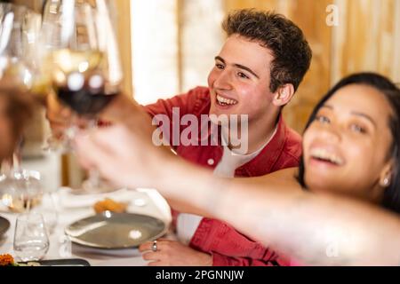 Un jeune homme heureux qui toaster des lunettes de vin avec des amis au restaurant Banque D'Images