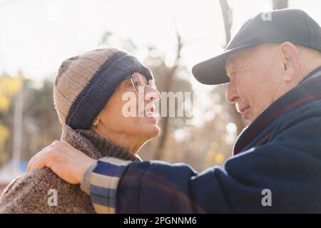 Couple senior portant des vêtements chauds discutant entre eux au parc Banque D'Images