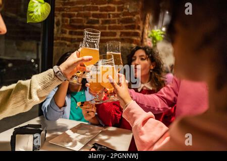 Des amis toaster des verres à bière à la table du restaurant Banque D'Images