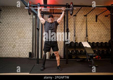 Homme mature avec une barbell de levage prothétique de jambe dans la salle de gym Banque D'Images