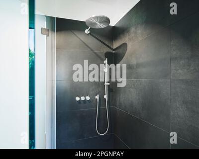 Douche au milieu du mur de carreaux noirs dans la salle de bains de l'appartement moderne Banque D'Images