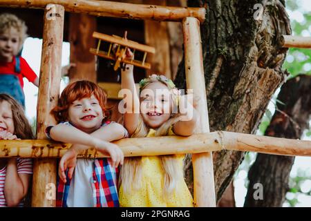 Fille souriante jouant avec l'avion jouet par des amis sur la maison d'arbre Banque D'Images