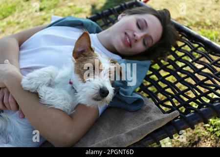 Jeune femme avec Jack Russell Terrier, située sur un hamac dans le parc Banque D'Images