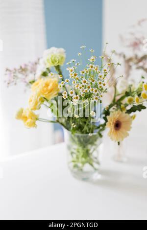 Fleurs jaunes et blanches dans un vase en verre sur une table Banque D'Images