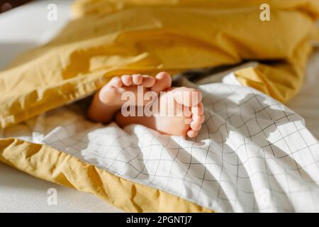 Les pieds de la jeune fille qui se délègue de la couverture sur le lit Banque D'Images