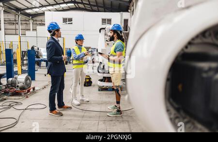 Les ingénieurs portant un casque de sécurité discutant en usine Banque D'Images