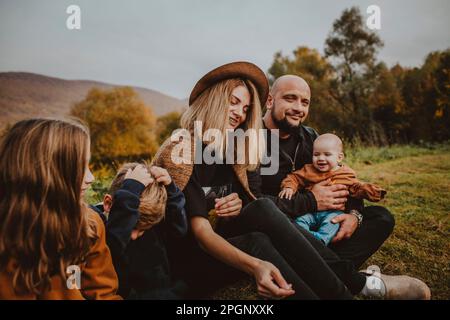 Famille passant du temps libre assis ensemble au parc Banque D'Images