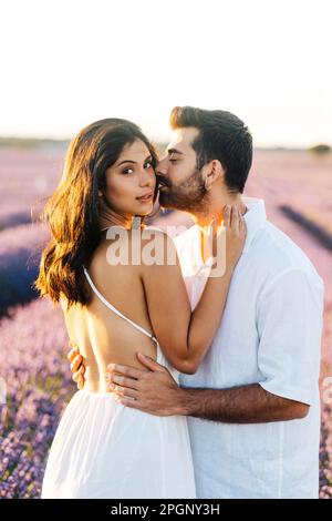 Homme embrassant la femme sur la joue debout dans le champ de lavande Banque D'Images