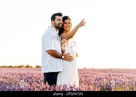 Bonne femme montrant la distance debout avec l'homme dans le champ de lavande au coucher du soleil Banque D'Images