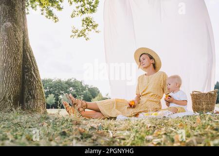 Femme attentionnés assise avec son fils dans le parc Banque D'Images