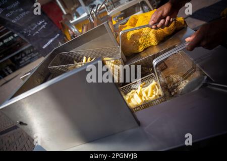 Faire frire des frites fraîchement coupées sur un marché Banque D'Images