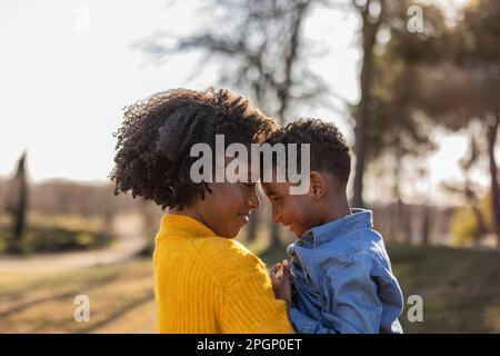 Mère et fils touchant les fronts dans le parc Banque D'Images