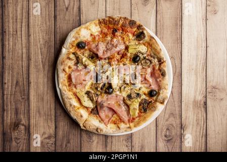 Pizza capricciosa est un style de pizza de la cuisine italienne préparée avec du fromage mozzarella, du jambon italien rôti au four, des artichauts, de la tomate et un peu d'edib Banque D'Images