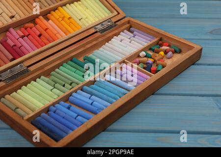 Jeu de dessin pastel dans une boîte sur table en bois bleu clair, gros plan Banque D'Images