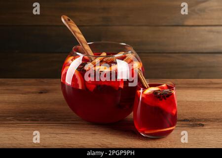 Verre et bol de délicieux punch aromatique sur table en bois Banque D'Images