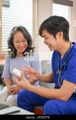 Portrait d'un médecin asiatique professionnel millénaire donnant une instruction et expliquant l'utilisation d'un médicament à une patiente âgée malade dans le c Banque D'Images