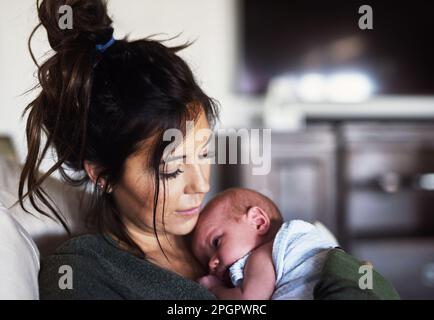 S'endormir dans les bras des mamans. une jeune femme joyeuse tenant son petit fils à la maison pendant la journée. Banque D'Images