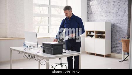 Homme utilisant une machine à photocopier dans Office. Imprimante et copieur Banque D'Images