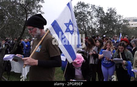 Un manifestant anti-gouvernement portant un drapeau israélien se joint à une prière tenue par des juifs religieux dans un plaidoyer pour l'unité et la délivrance divine des tensions croissantes sur la révision judiciaire du pays devant la Cour suprême israélienne sur 22 mars 2023 à Jérusalem, en Israël. Le gouvernement Netanyahou avance sur la proposition de révision du système judiciaire qui limiterait la capacité de la Cour suprême israélienne à réviser et à faire tomber les lois qu'elle juge inconstitutionnelles. Banque D'Images