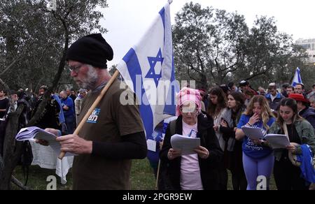 Un manifestant anti-gouvernement portant un drapeau israélien se joint à une prière tenue par des juifs religieux dans un plaidoyer pour l'unité et la délivrance divine des tensions croissantes sur la révision judiciaire du pays devant la Cour suprême israélienne sur 22 mars 2023 à Jérusalem, en Israël. Le gouvernement Netanyahou avance sur la proposition de révision du système judiciaire qui limiterait la capacité de la Cour suprême israélienne à réviser et à faire tomber les lois qu'elle juge inconstitutionnelles. Banque D'Images