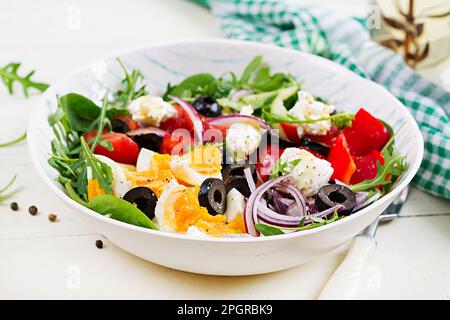 Petit déjeuner. Salade grecque et œufs durs. Salade de légumes frais avec tomates, concombres, olives, arugula et fromage à la crème. Cuisine tendance. Banque D'Images