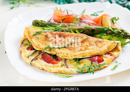 Petit déjeuner cétogène. Omelette aux tomates, oignon rouge, sandwich au saumon et asperges grillées. Frittata italien. Keto, déjeuner cétogène. Banque D'Images