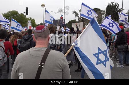 Un manifestant religieux porte un drapeau israélien tandis que des étudiants et d'autres manifestants anti-gouvernement branchent des slogans lors d'une manifestation contre la coalition de droite du Premier ministre israélien Benjamin Netanyahu et ses propositions de changements judiciaires sur 23 mars 2023 à Jérusalem, en Israël. Banque D'Images