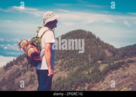 Un homme âgé debout contre un magnifique paysage de montagne avec sac à dos. Autre mode de vie de retraite personnes âgées âge mûr appréciant libéré Banque D'Images