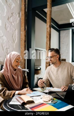 Des femmes et des hommes joyeux et multiraciaux travaillent ensemble en atelier Banque D'Images