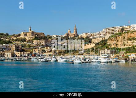 Le port de Mġarr sur l'île de Gozo, Malte. Belle ville sur les falaises et les collines en arrière-plan le jour ensoleillé du printemps. Banque D'Images