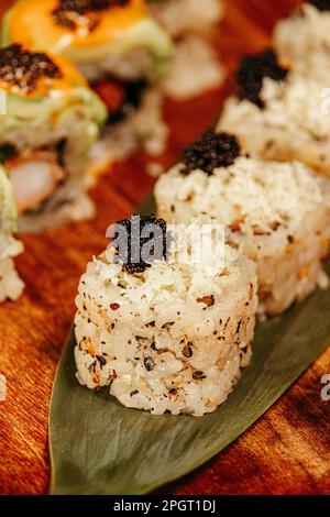 Une table en bois avec un assortiment de délicieux sushis et de petits pains aux légumes Banque D'Images