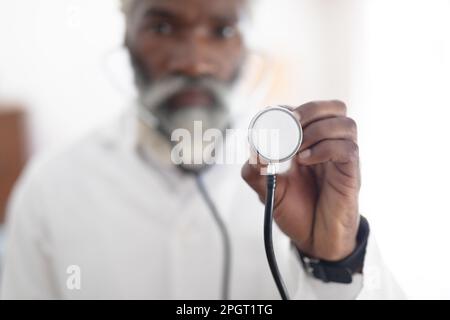 Afro-américain senior médecin portant un manteau blanc regardant la caméra tenant le stéthoscope. professionnel de la santé au travail. Banque D'Images