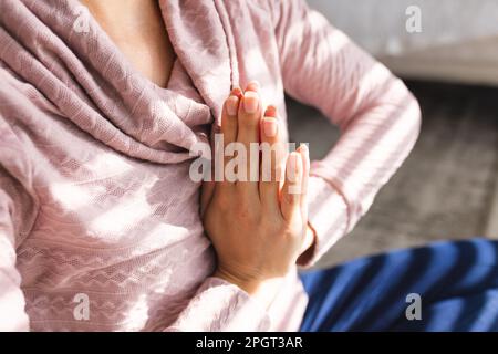 Mi-section de la jeune femme caucasienne méditant en position de prière tout en étant assise à la maison. Non modifié, yoga, zen, style de vie, exercice, fitness et maison c Banque D'Images