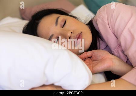 Bonne femme asiatique couchée sur un oreiller blanc sur son lit. Style de vie, temps libre et détente. Banque D'Images