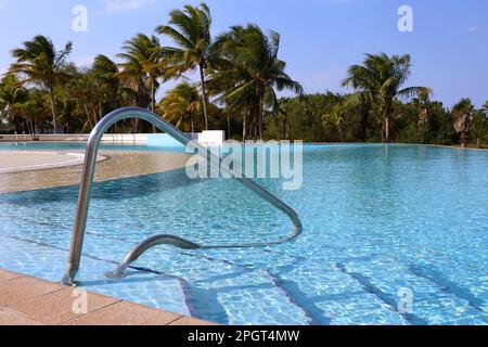 Vue sur les marches de la piscine avec une balustrade contre les cocotiers. Vacances sur la plage sur l'île tropicale Banque D'Images