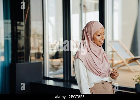 Bonne femme d'affaires musulmane portant un foulard souriant au bureau Banque D'Images