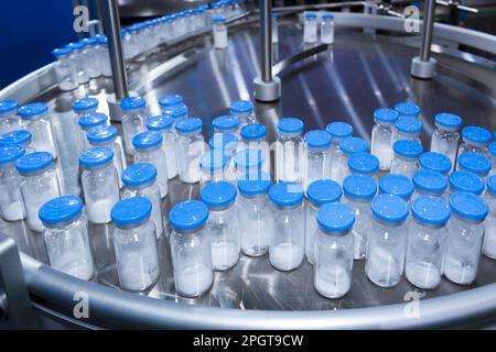 flacon en verre de médecine dans la chaîne de production pharmaceutique, conduit sur un tapis convoyeur au niveau de la machine de remplissage dans la fabrication de vaccins médicaux. santé et medi Banque D'Images