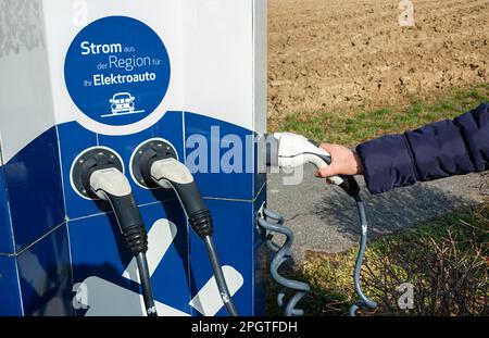 Seengen, Suisse - 23 février 2023: Femme tenant une prise de charge électrique EV pour charger un véhicule. Banque D'Images